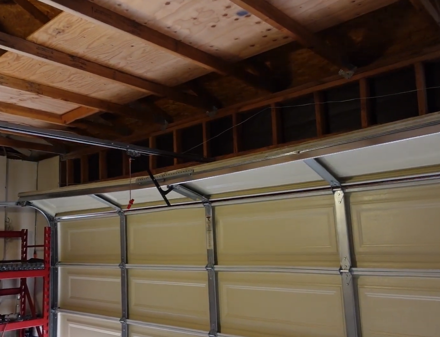 Close-up of a garage door opener rail, trolley, and manual release cord